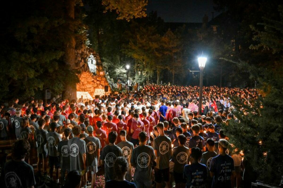 Incoming students gather at night at the grotto